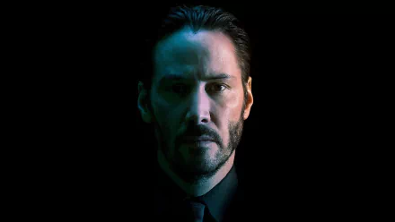 A striking HD wallpaper featuring Keanu Reeves as John Wick, showcasing a dramatic portrait with a dark background and moody lighting.