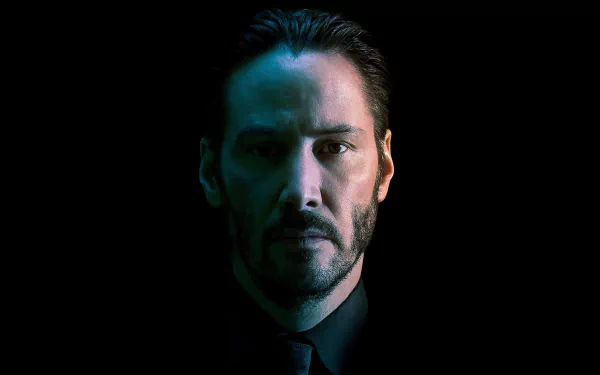 A striking HD wallpaper featuring Keanu Reeves as John Wick, showcasing a dramatic portrait with a dark background and moody lighting.