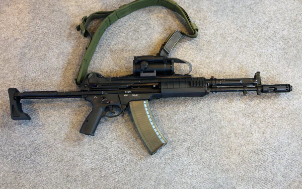 HD PC desktop wallpaper of a man-made assault rifle AK-12 laid horizontally on a carpeted surface, fitted with a sling and translucent curved magazine.