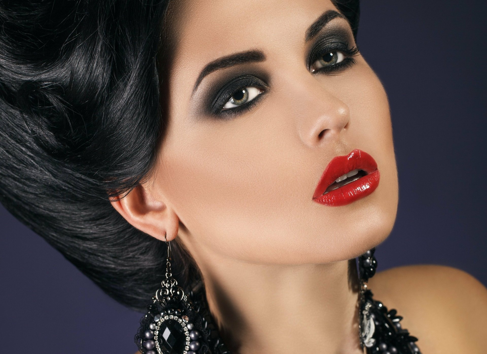 HD PC desktop wallpaper featuring a close-up of a woman’s face with bold makeup, dark hair, and striking red lipstick against a dark background.