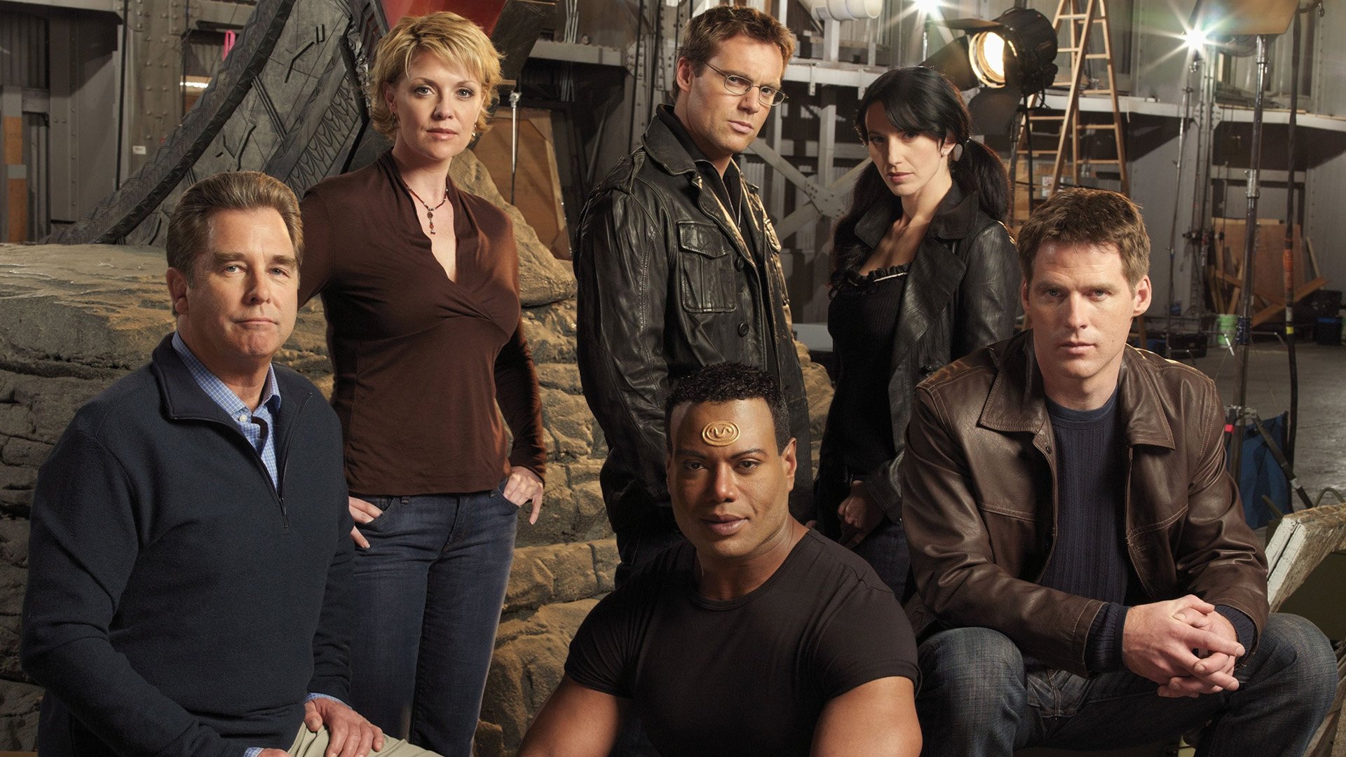 Stargate SG-1 TV show cast posed on an industrial set with dramatic lighting — HD PC desktop wallpaper/background.