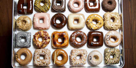 HD PC desktop wallpaper featuring a vibrant assortment of various glazed and decorated doughnuts arranged in neat rows against a white background.