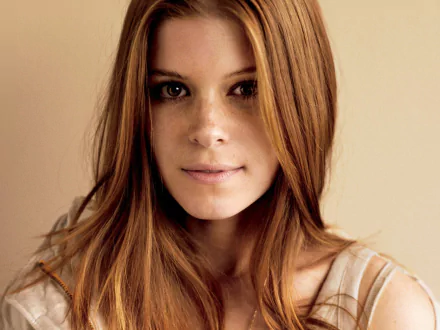 HD desktop wallpaper featuring a close-up portrait of celebrity Kate Mara with natural makeup and loose red hair against a plain background.