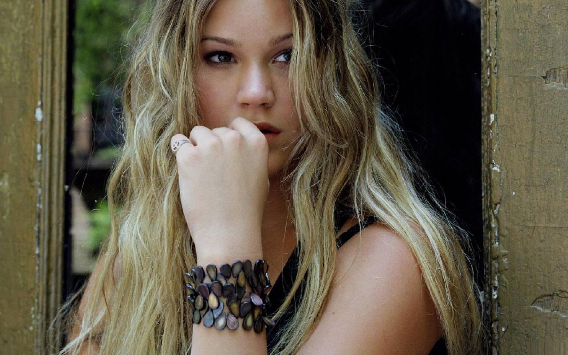 HD PC desktop wallpaper: close-up portrait of a contemplative female soul singer with long blonde hair and layered bracelet, music-themed background.