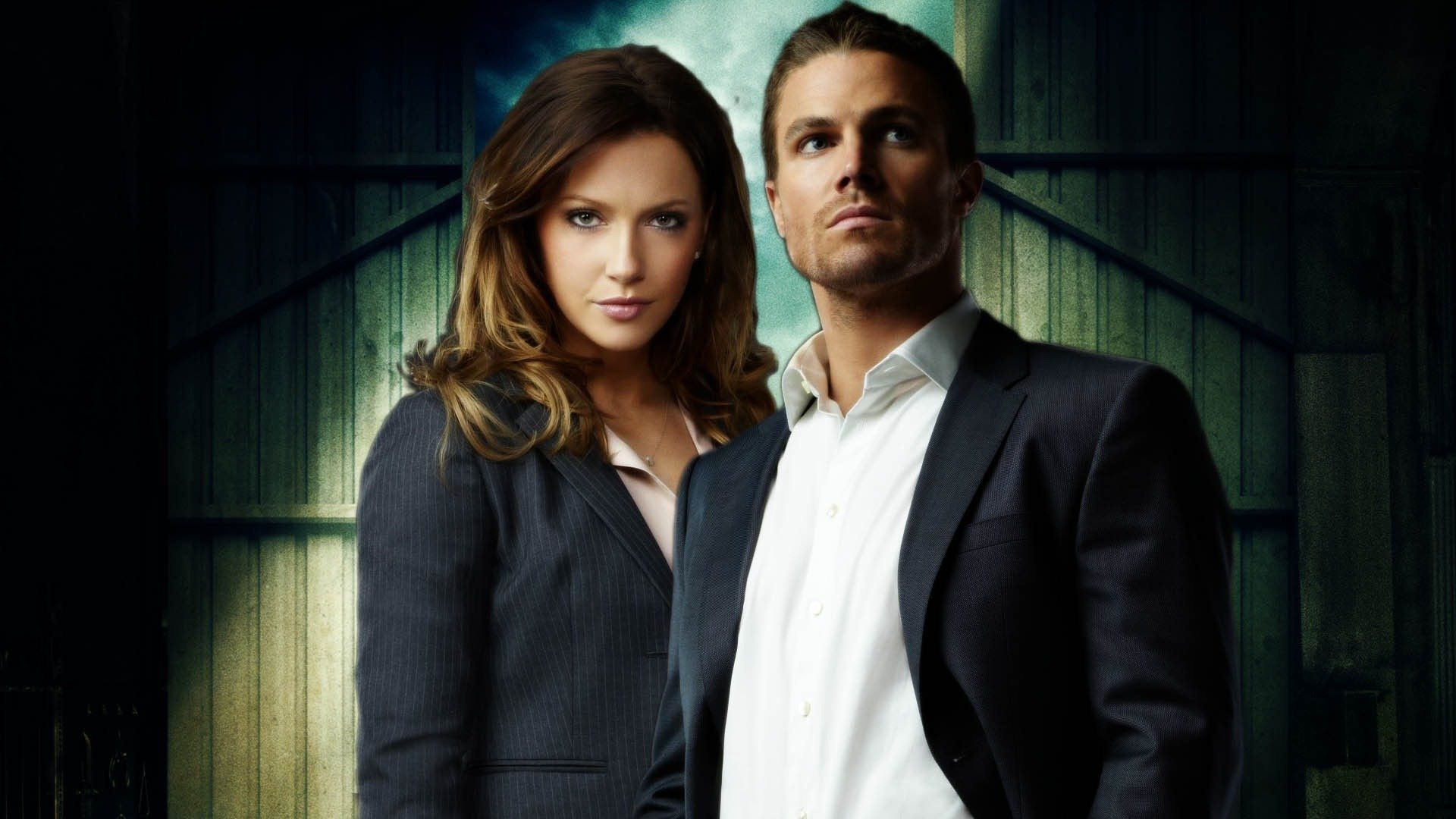 HD desktop wallpaper featuring Stephen Amell and a co-star from the TV show Arrow, both dressed in formal attire against a dark, moody background.