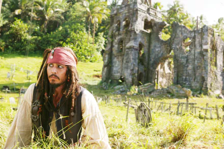 Jack Sparrow, portrayed by Johnny Depp, gazes thoughtfully amidst lush greenery and ancient ruins in this vivid wallpaper from *Pirates of the Caribbean: Dead Man's Chest*.
