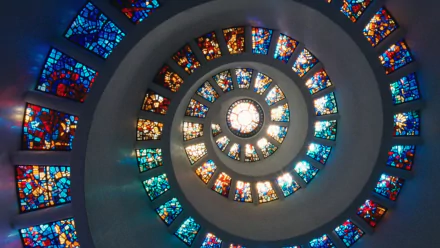 HD PC desktop wallpaper of a spiral stained-glass installation inspired by the movie The Tree of Life, glowing concentric panels of blue, gold and red.