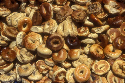 HD PC desktop wallpaper showing a close-up pile of assorted mini bagels and bagel chips in warm golden-brown tones.