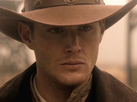 A HD desktop wallpaper featuring Jensen Ackles as Dean Winchester from the TV show *Supernatural*, showcasing a close-up of his intense expression under a wide-brimmed hat.