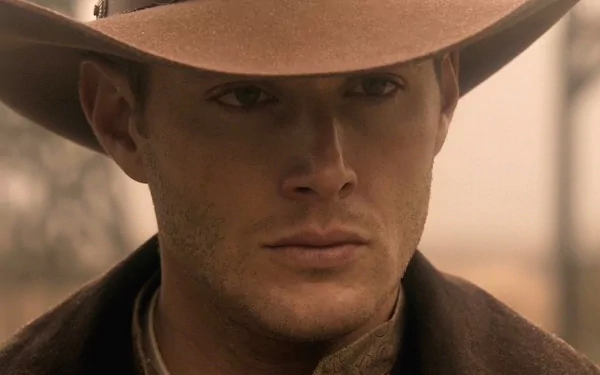 A HD desktop wallpaper featuring Jensen Ackles as Dean Winchester from the TV show *Supernatural*, showcasing a close-up of his intense expression under a wide-brimmed hat.