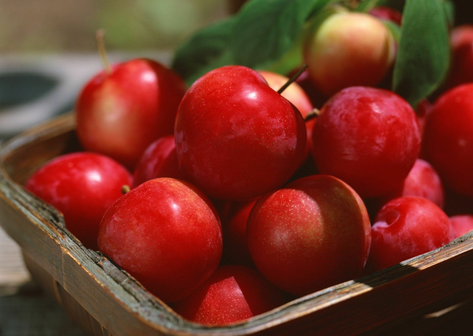 HD desktop wallpaper featuring a close-up of fresh, vibrant red apples in a rustic wooden crate, highlighting the natural texture and color of the fruit.