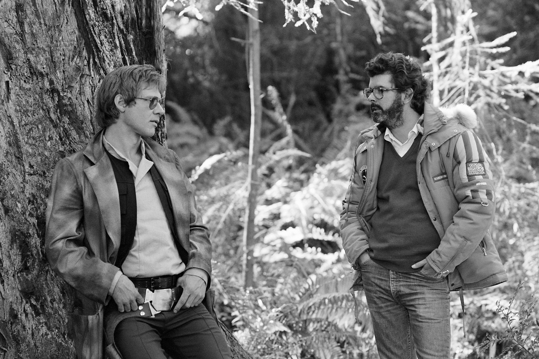 Black-and-white HD PC desktop wallpaper showing a behind-the-scenes moment from Star Wars Episode VI: Return of the Jedi with two men in a forest setting.