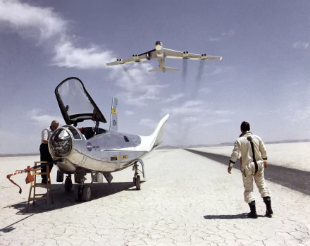 A Boeing B-52 Stratofortress flies overhead as a pilot approaches the Northrop HL-10 aircraft, showcasing a striking moment in aviation history captured in HD.