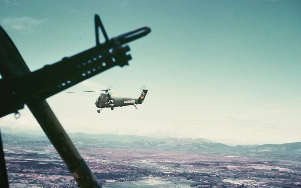 Military Sikorsky H-34 helicopter in flight over snowy terrain, framed from a cockpit with a gun silhouette — HD PC desktop wallpaper and background.