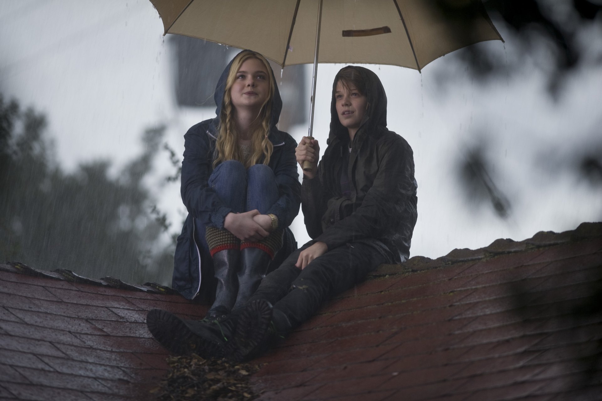 Two young people sit on a rain-soaked rooftop under an umbrella, cinematic scene from the film We Bought a Zoo — HD PC desktop wallpaper.