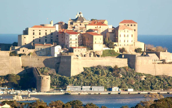 Sunlit man-made citadel of Calvi, Haute-Corse: stone ramparts and terracotta roofs on a coastal promontory, HD PC desktop wallpaper and background.