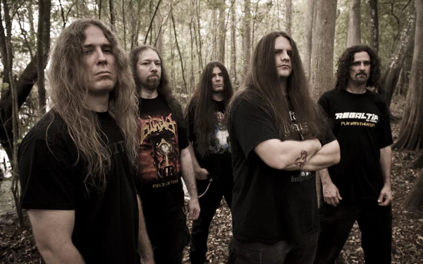 Five long-haired men in black metal shirts stand in a misty forest; moody desaturated photo, 2K Quad HD music desktop wallpaper.