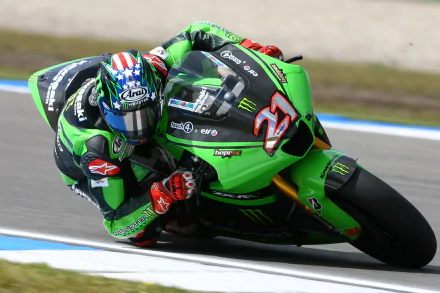 A Kawasaki Ninja motorcycle speeds around a track, with a rider leaning in for a sharp turn, showcasing the bike's sleek design and performance in this HD desktop wallpaper.