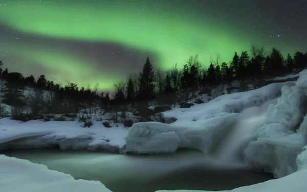 4K Ultra HD PC desktop wallpaper: a snow-covered river and frozen banks beneath a vivid green aurora borealis arching over a dark treeline.
