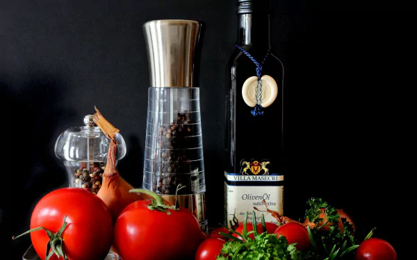HD PC desktop wallpaper still life: Mediterranean food scene with ripe tomatoes, herbs, olive oil bottle and a pepper grinder on a dark background.