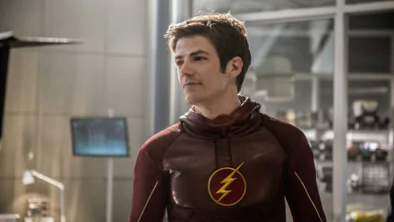 Barry Allen, portrayed by Grant Gustin, stands in his Flash suit in a scene from the TV show The Flash (2014), surrounded by a high-tech environment.