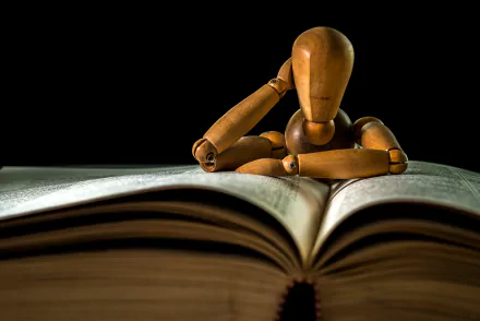 A man-made wooden mannequin resting its head on an open book, captured in sharp detail as a 4K Ultra HD PC desktop wallpaper.