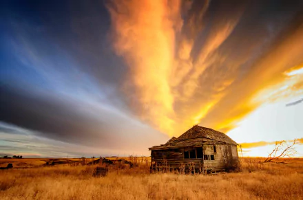 4K Ultra HD PC desktop wallpaper background: a weathered man-made cabin in tall dry grass beneath a dramatic golden-orange sunset sky.
