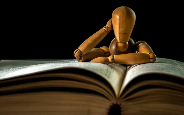 A man-made wooden mannequin resting its head on an open book, captured in sharp detail as a 4K Ultra HD PC desktop wallpaper.