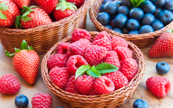 A vibrant assortment of fresh strawberries, blueberries, and raspberries in woven baskets, showcasing a delicious variety of berries against a rustic backdrop. 4K Ultra HD wallpaper.