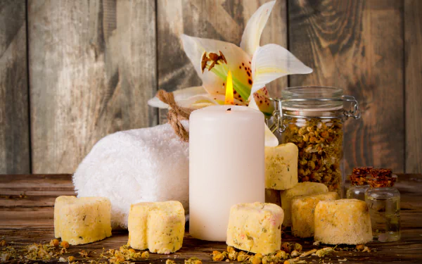 A tranquil still life featuring a candle, soap bars, a towel, and a flower, set against a warm wooden background, creating a soothing spa atmosphere. 