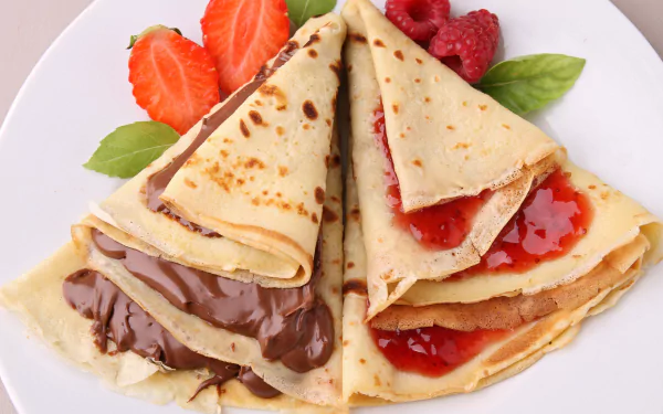 A delicious assortment of crêpes filled with chocolate and jam, garnished with fresh strawberries and raspberries, showcased as a vibrant 4K Ultra HD desktop wallpaper.
