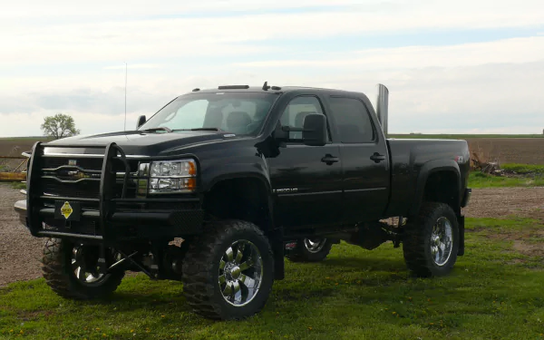 Black Chevrolet Silverado truck parked on grass under a cloudy sky, presented as an HD PC desktop wallpaper and background.