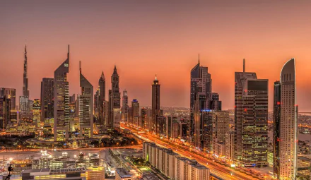 HD desktop wallpaper showcasing Dubai's man-made skyline illuminated at sunset with towering skyscrapers and vibrant city lights.