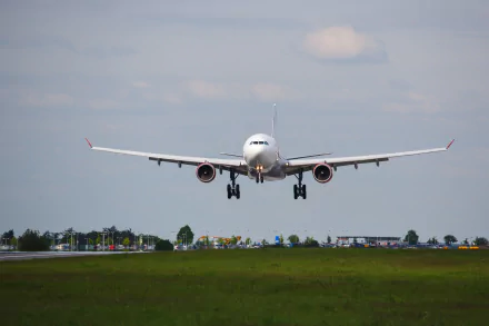 An Airbus A330 aircraft approaches for landing, with its landing gear extended. The background features a clear sky and hints of greenery, showcasing the vehicle in action.