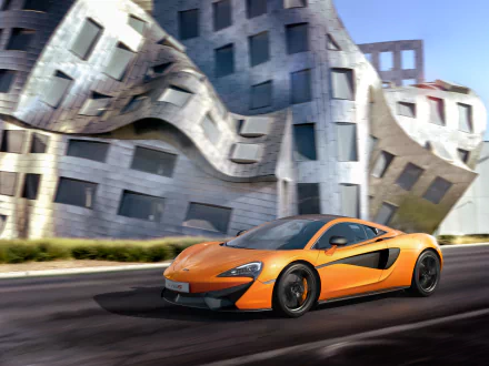 Orange McLaren 570S supercar driving past a modern, wavy architectural building, captured in a 4K Ultra HD desktop wallpaper.