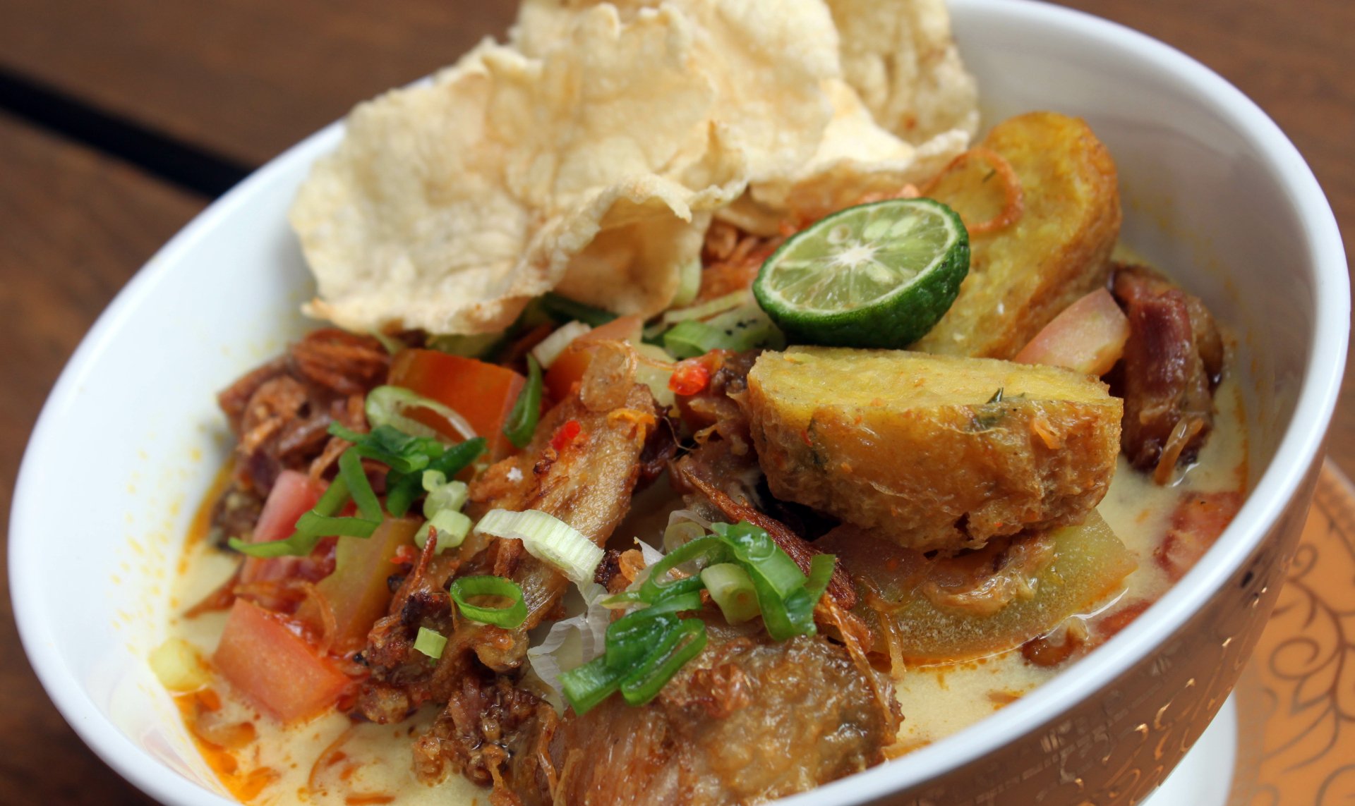 5K Ultra HD PC desktop wallpaper/background of Soto food: close-up bowl of Indonesian soup with shredded meat, fried tofu, lime slice, scallions and crispy crackers.