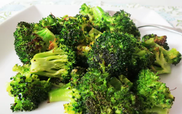 Roasted broccoli florets on a white plate, vibrant green food; 4K Ultra HD PC desktop wallpaper and background.