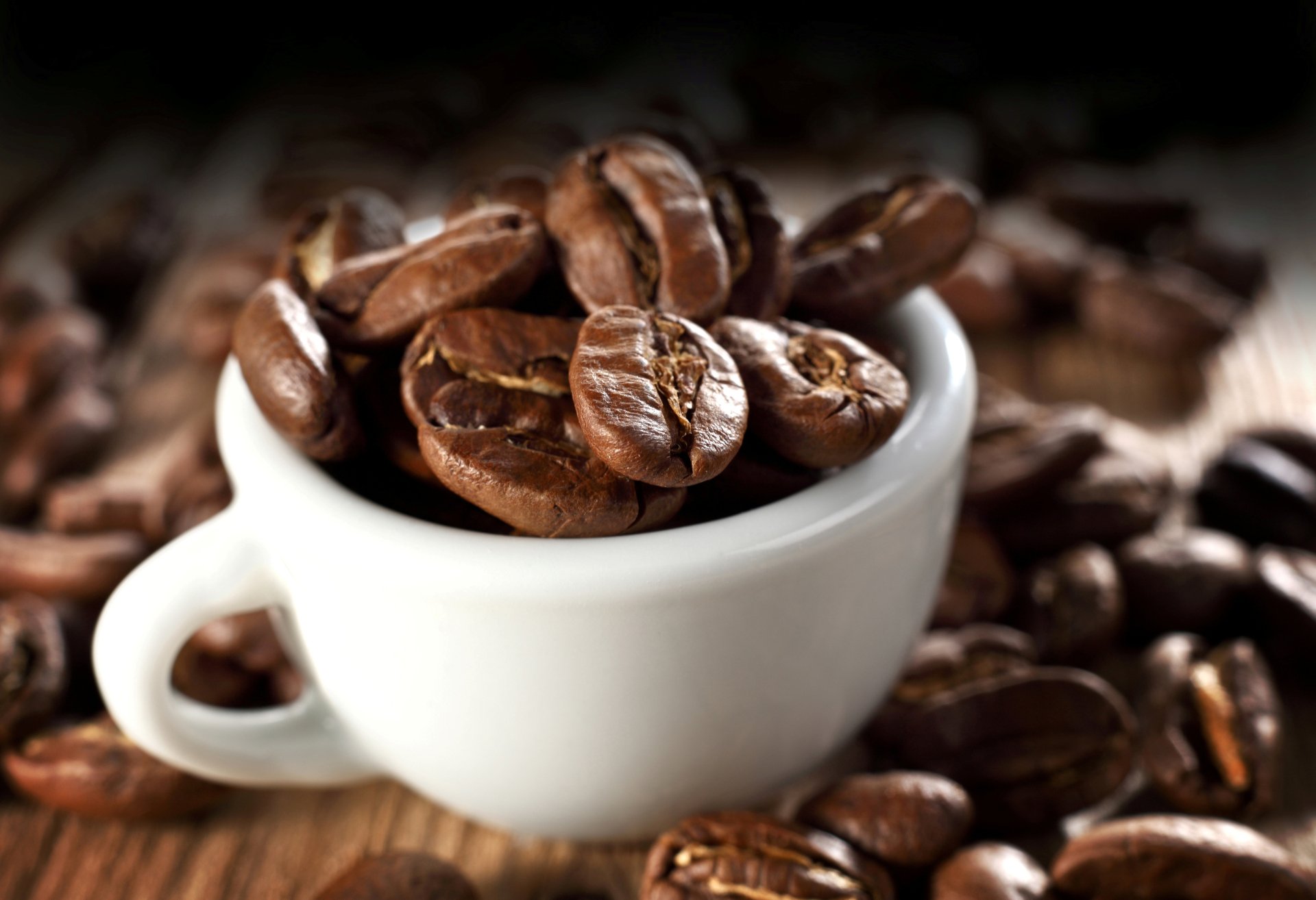 Close-up of a white cup filled with roasted coffee beans, surrounded by more beans, captured in 4K Ultra HD for a rich, detailed coffee-themed desktop wallpaper.