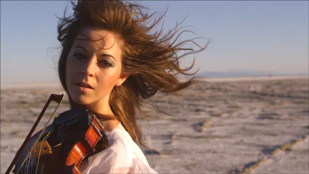 HD PC desktop wallpaper featuring Lindsey Stirling playing violin in an open desert landscape, capturing dynamic motion and musical expression.