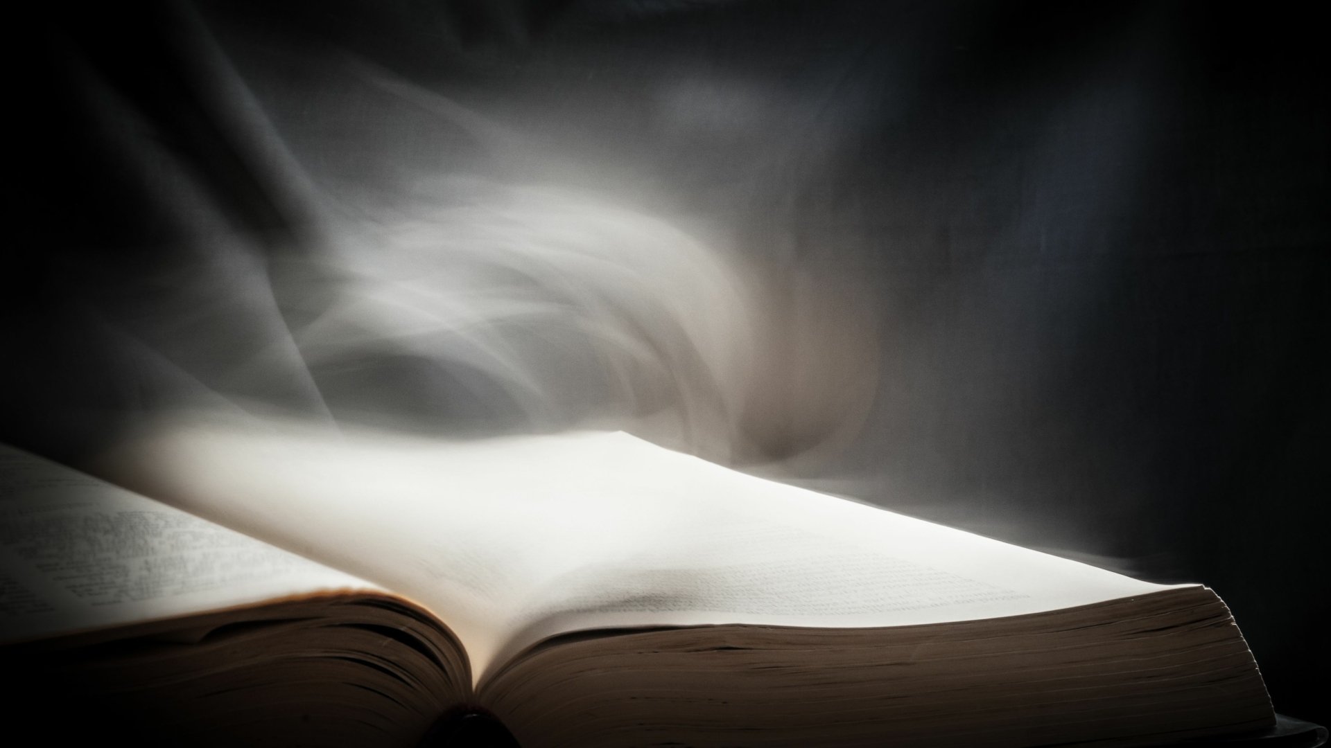 A close-up of an open book with ethereal light and smoke rising above, rendered in 4K Ultra HD for a striking PC desktop wallpaper background.
