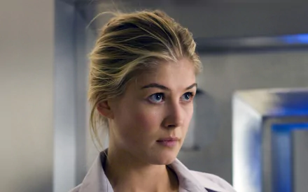 HD PC desktop wallpaper featuring a close-up of celebrity Rosamund Pike with a focused expression in a softly lit indoor setting.