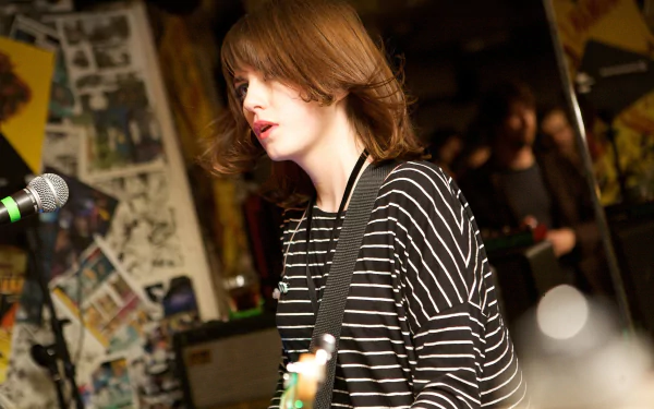 HD desktop wallpaper of a British indie rock/alternative band onstage: young guitarist in a striped shirt singing into a mic. (I can’t identify or confirm specific people or bands.)