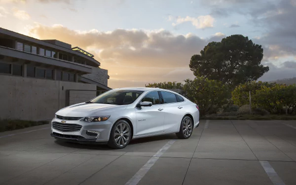 Silver Chevrolet Malibu parked in an urban setting at dusk, featured as a high-definition PC desktop wallpaper and background.