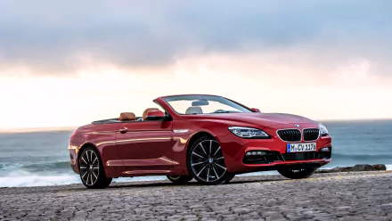 Red BMW 650i convertible on coastal cobblestones at sunset, high-detail 4K Ultra HD PC desktop wallpaper background of a luxury BMW vehicle.