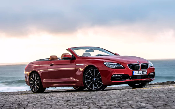 Red BMW 650i convertible on coastal cobblestones at sunset, high-detail 4K Ultra HD PC desktop wallpaper background of a luxury BMW vehicle.