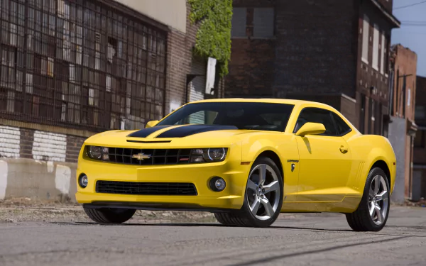 A vibrant yellow Chevrolet Camaro parked in an urban setting, showcasing its sleek design. This HD image serves as an eye-catching desktop wallpaper.