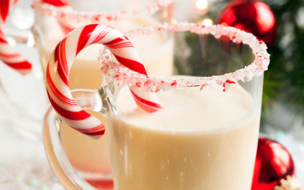 A festive HD wallpaper featuring glasses of milk adorned with crushed candy cane rims and striped candy canes, set against a holiday-themed backdrop with Christmas decorations.