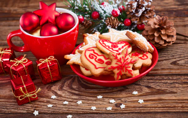 A festive 4K Ultra HD wallpaper featuring Christmas cookies, red ornaments in a mug, pine cones, and small wrapped gifts on a wooden holiday background.