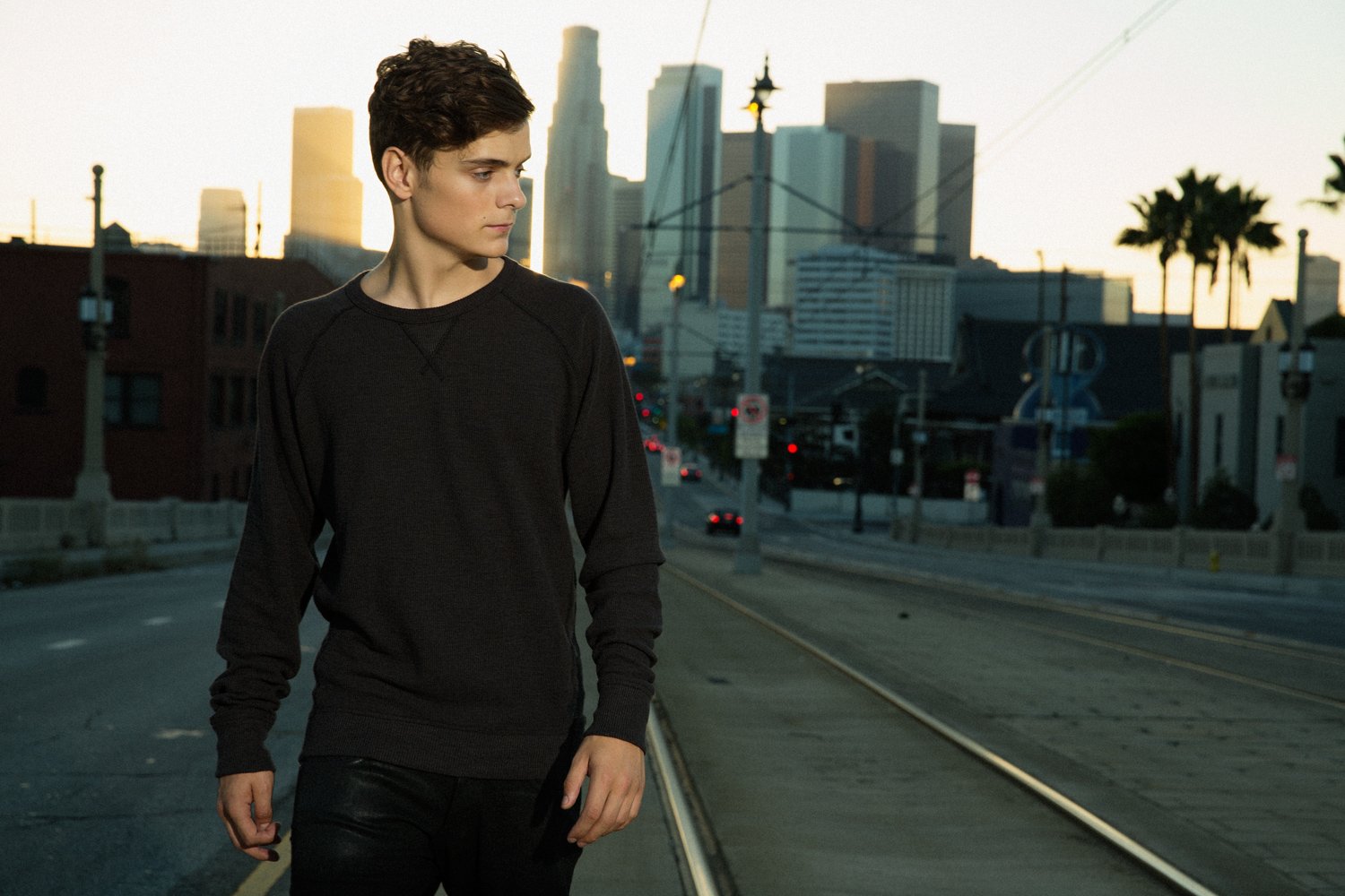 HD desktop wallpaper featuring music artist Martin Garrix walking on an urban street with tall buildings in the background.