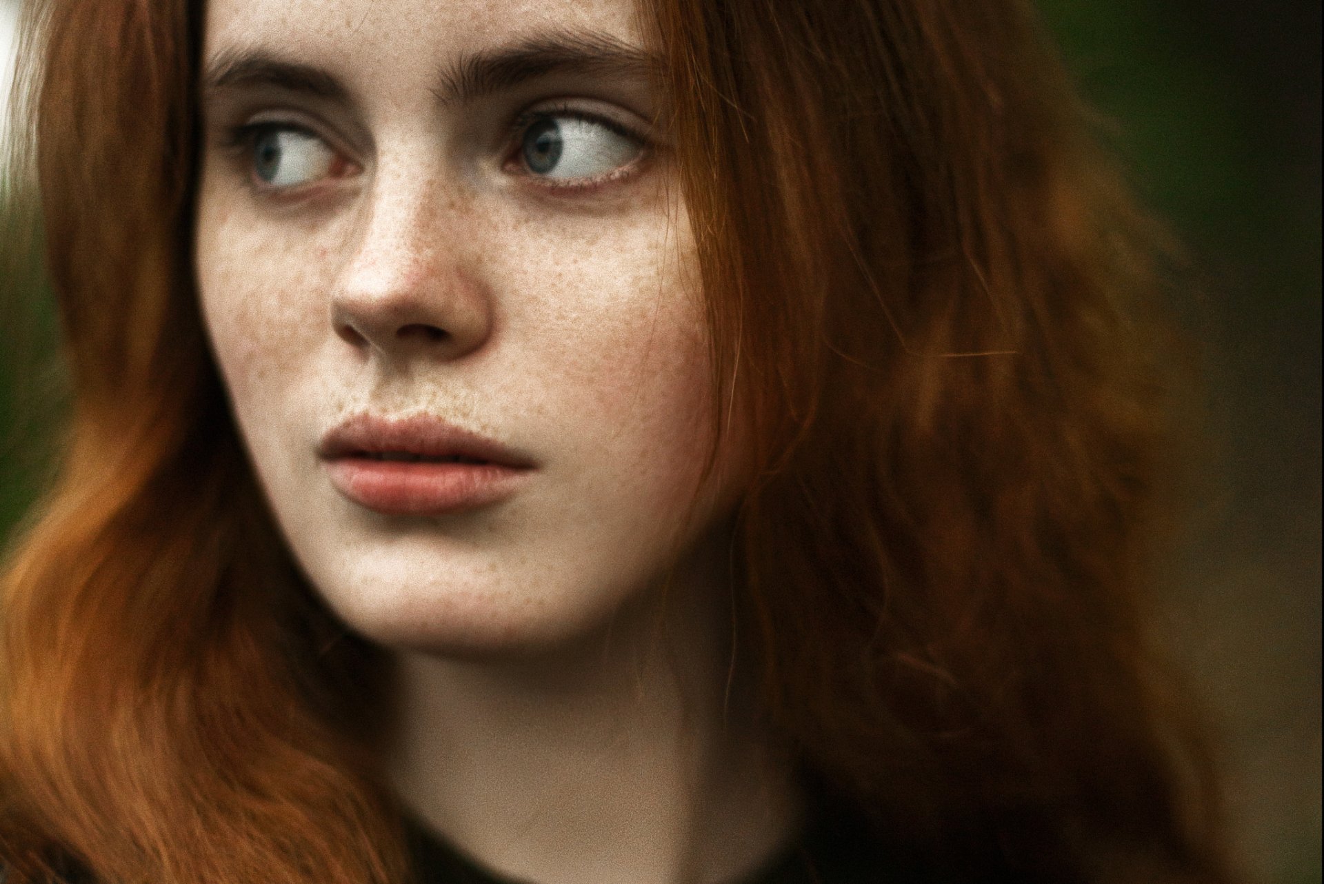 Close-up HD desktop wallpaper of a redhead woman’s face with freckles, showcasing natural beauty and soft lighting.